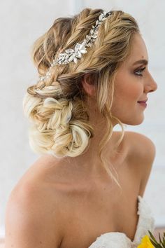 a woman wearing a bridal hair piece with flowers in her hair and holding a bouquet