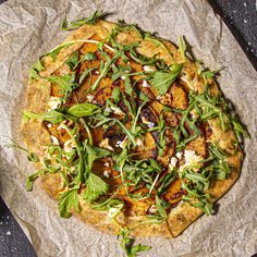 a pizza sitting on top of a piece of paper covered in greens and other toppings