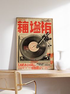 an old record player poster on a wall above a desk with a chair and vase