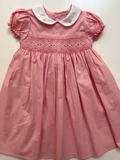 Introducing our beautiful baby pink summer dress.   This dress is made of super soft cotton material and comes with no lining or under skirt.  Perfect summer dress 💕 What we love.   ✨Made from 100% cotton fabric ✨Hand embroidered and smocked from chest to waist.  ✨It has peter pan collar with embroidered yellow roses.  ✨Tie at the back with buttons.  ✨Sophisticated Details ✨Ethically made with love by my mum We are based in Brisbane, Australia and we ship Australia wide.  Thank you for supporting small business ♥️ Feminine Cotton Dress With Smocked Bodice, Feminine Cotton Smocked Summer Dress, Pink Smocked Short Sleeve Dress For Garden Party, Cotton Smocked Short Sleeve Dress For Daywear, Cotton Short Sleeve Smocked Dress For Daywear, Cute Pink Smocked Dress With Smocked Back, Feminine Pink Smocked Short Sleeve Dress, Feminine Pink Smocked Dress With Short Sleeves, Feminine Pink Short-sleeved Smocked Dress