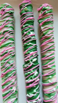 green and pink sprinkled donuts sitting on top of a white table next to each other