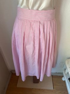 "This gorgeous button down pink and white skirt is so pretty! The composition is 50% polyester and 50% cotton. Would be perfect paired with cowboy boots and a prairie shirt, or with a white blouse tucked in and leather huaraches. Our best guess is that it is a women's medium to large, it is marked a size 11/12. But please check the measurements given below to ensure a proper fit. It was made in the early 1980's in the USA by Avon Fashions, and buttons completely down. It is in good condition wit Casual Pink A-line Bottoms, Summer Striped Cotton Skirt, Striped Cotton Skirt For Summer, Spring Pink A-line Bottoms, Striped Cotton Relaxed Skirt, Spring Striped Flared Skirt, Pink Full Skirt Bottoms For Day Out, Pink Flared Cotton Skirt, Relaxed Striped Skirt For Spring