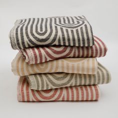 four folded towels stacked on top of each other in different colors and patterns, with one folded up to the side