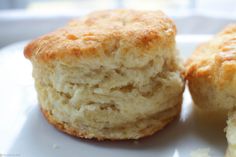 two biscuits sitting on top of a white plate next to each other with one bite taken out