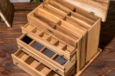 a wooden box with drawers on top of a table next to a pen and pencil holder