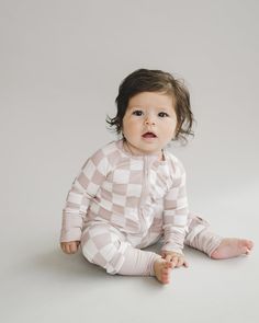 Embrace the cuteness and comfort with our Latte Checkered Bamboo Zip Baby Jumpsuit. Designed for your little one’s all-day comfort, this jumpsuit is ultra-soft and stretchy, perfect for playtime, nap time, or any cozy cuddle time. Made from 95% bamboo viscose and 5% spandex, it features practical fold-over mittens and footies for sizes up to 12-18 months, ensuring your baby’s hands and feet stay warm. The two-way zipper simplifies diaper changes, making it convenient for parents while keeping ba Playful Long-sleeve Bubble Romper For Loungewear, Playful Long Sleeve Bubble Romper For Loungewear, Super Soft Long Sleeve Onesie For Playtime, Playful Fitted Jumpsuits And Rompers For Loungewear, Playful White Long Sleeve Jumpsuits And Rompers, White Long Sleeve Playful Jumpsuit, Playful Pink Bodysuit For Loungewear, Soft Fitted Onesie For Playtime, Pink Long Sleeve Jumpsuits And Rompers For Playtime