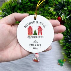 a hand holding a christmas ornament with two houses on it and the words neighborss by chance