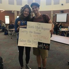 two people standing next to each other holding a sign