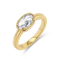 a yellow gold ring with an oval cut white topazte in the center, set on