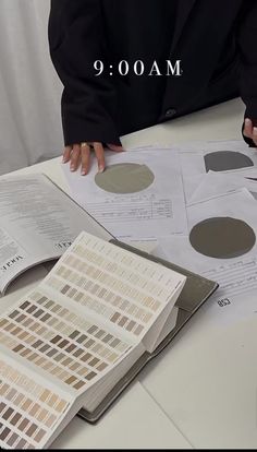 a person sitting at a table with some papers and paint swatches on top of it