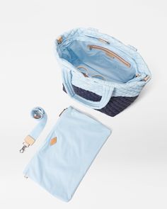 a blue purse and accessories on a white surface, including a zippered pouch with the contents attached to it