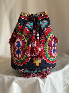 "Large Drawstring Silk Petit Point Handbag created and handmade in Uzbekistan. Lined with silk and cotton ikat fabric, hand woven silk straps, lots of tassels and a drawstring closure. Drawstring goes through brass grommets and ties with tassels at the end of the drawstring. Each handbag is hand drawn onto cotton canvas, inspired by original designs from Uzbekistan textile history.  7.5\" high x 10.5\" width(21\" in diameter), top opening 21\" wide, approx. 61\" strap x 3/4\" width. I can shorte Traditional Handwoven Pouch Bag, Traditional Multicolor Crochet Bag, Traditional Multicolor Woven Bags, Traditional Woven Pouch Bag, Bohemian Potli Bag With Multicolor Embroidery And Handwork, Traditional Woven Crochet Travel Bag, Traditional Multicolor Crochet Bag For Everyday Use, Traditional Crochet Woven Bag For Travel, Traditional Multicolor Crochet Bag For Everyday