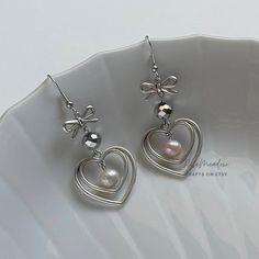 "Handmade Beaded Earrings ✿ Made with freshwater pearls, glass crystal beads, and metal accents ✿ Silver, deep grey, and pearlescent peach ✿ The earrings are 2.2\" long Fish Hook Options ✿ The Titanium fish hook is hypoallergenic and ideal for sensitive skin ✿ The regular fish hook is made of nickel free metal, it is not hypoallergenic" Silver Pearl Beaded Earrings For Party, Silver Pearl Heart Earrings, Silver Pearl Heart-shaped Earrings, Silver Heart-shaped Pearl Earrings, Handmade Silver Pearl Beaded Earrings, Silver Pearl Beaded Drop Earrings, Metal Pearl Earrings With Dangling Beads For Gift, Silver Pearl Earrings With Dangling Beads As Gift, Grey Accessories