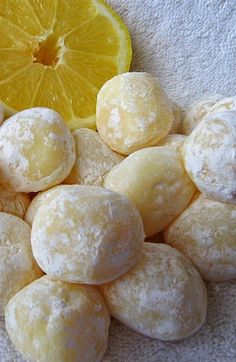 a pile of powdered doughnuts next to a lemon slice