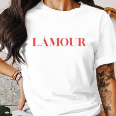 Our T-shirt with the striking red lettering "LÁmour" is made of high-quality materials and not only offers a fashionable look, but also optimal comfort. The shirt is made of 100% cotton and is available in different sizes to ensure a perfect fit. With its elegant yet casual design, this T-shirt is a real eye-catcher. The LÁmour T-shirt is ideal for everyday wear, whether it's for a relaxing day at home or a trip into town. The bright red lettering gives every outfit a special touch, while the so Red Crew Neck T-shirt With Letter Print, Trendy Red T-shirt With Logo Print, Red Letter Print Shirt For Summer, Red Crew Neck T-shirt With Name Print, Trendy Red T-shirt With Text Print, Red Short Sleeve T-shirt With Letter Print, Red Shirt With Text Print For Summer, Red Slogan Crew Neck Shirt, Red Graphic Tee With Letter Print