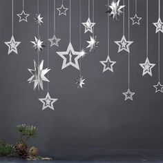 white stars hanging from the ceiling in front of a gray wall with pineconi