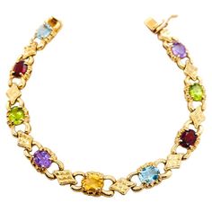 This colorful bracelet has a beautiful mix of birthstone colors in sturdy 14 karat yellow gold. The oval gemstones are blue topaz, garnet, peridot, amethyst, and citrine. These stones can represent many different things. As birthstones, they represent December, January, August, February, and November. What will they mean for you? Perhaps the first initials of each month or stone spells something special to you! The oval gems are each 7 mm by 5 mm set in links forming a slim line bracelet that lo Luxury Birthstone Bracelets In Fine Jewelry Style, Yellow Gold Oval Multi-stone Bracelet, Luxury Multi-stone Gold Bracelet, Luxury Yellow Gold Multi-stone Bracelet, Vintage Oval Multi-stone Bracelets, Luxury Multicolor Multi-stone Gold Bracelet, Amethyst And Citrine, Colorful Bracelet, Birthstone Colors