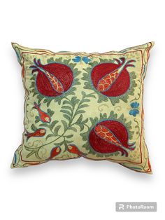 an embroidered pillow with red and green flowers on it