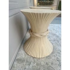 a white vase sitting on top of a cement floor next to a wall and door