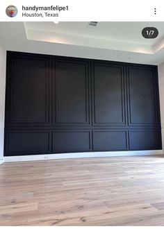 an empty room with dark wood paneling and white walls