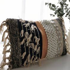 a black and white pillow sitting on top of a table next to a potted plant