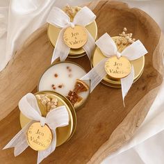 three personalized candles in gold tins on a wooden platter with white ribbon