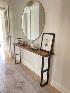 a table with a mirror and some pictures on top of it next to a doorway