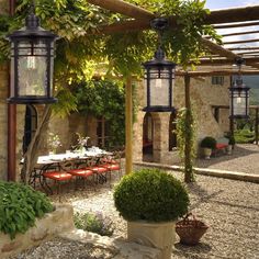 an outdoor dining area with potted plants and hanging lanterns in the middle of it