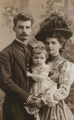 an old photo of a man and woman with a baby in their arms, standing next to each other