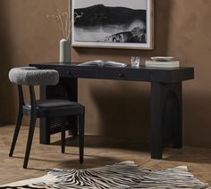 a zebra print rug in front of a desk with a chair and painting on the wall