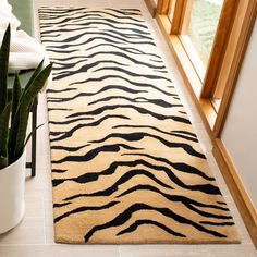 a zebra print rug on the floor next to a potted plant in front of a window