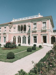 a large pink house sitting on top of a lush green field