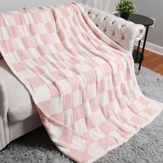 a pink and white checkered blanket sitting on top of a couch next to a chair