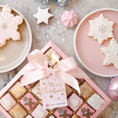 pink and white christmas cookies in a gift box on a marble table with other decorations