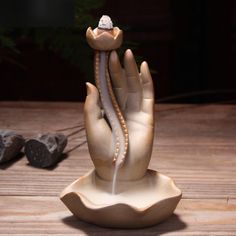 a hand with a ring on it is spewing water into the air from its palm