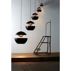 a group of lights hanging from the side of a white wall next to a ladder