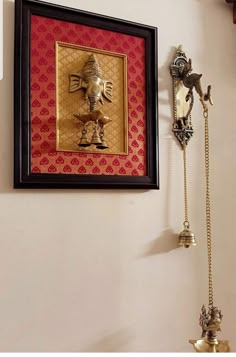 a wall mounted phone next to a gold and red frame with an elephant on it