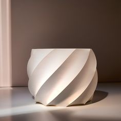 a large white vase sitting on top of a floor next to a window sill