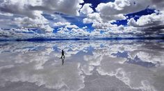 a person standing in the middle of a large body of water with clouds behind them