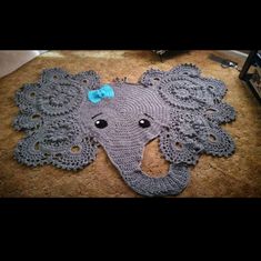 a crocheted elephant rug with a blue bow on it's head is laying on the floor