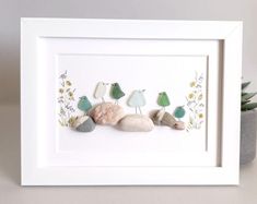 three birds sitting on top of rocks in front of a white framed artwork piece with succulents and flowers