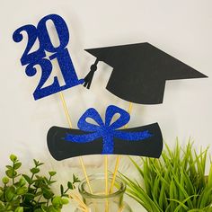 graduation cake toppers in the shape of hats and diplomas with blue glitter on them