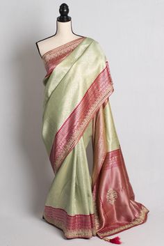 Elevate your ethnic wardrobe with Bengal Looms' exquisite Semi Silk Crystal Work Banarasi Saree in Pista Green and Pink. Intricately designed with stone and mirror embroidery along the border, this saree harmoniously blends tradition and modernity. Crafted from semi silk  perfect for any special occasion. Shop now and enjoy free fast shipping from within the USA, ensuring that your piece of timeless beauty arrives promptly. Rediscover the charm of Indian craftsmanship with this exclusive Banarasi saree from Bengal Looms. Semi Silk is a sysnthetic mixed fabric. Color : Pista White and Pink Blouse Piece : Yes ( cut and separated from the saree ). Fall Pico : Yes.  Care: Dry-Clean Only.  Do Note : Any displacements to stones, sequins, beads or embroidery cannot be deemed as defect in the garm Pista Green Raw Silk Traditional Wear For Festive Season, Festive Pista Green Raw Silk Traditional Wear, Semi-stitched Pista Green Jamawar Traditional Wear, Pista Green Traditional Wear With Zari Work In Jamawar, Pista Green Art Silk Churidar With Pallu, Pista Green Art Silk Salwar Kameez With Pallu, Pista Green Pallu Salwar Kameez In Art Silk, Festive Pista Green Tussar Silk Blouse Piece, Pista Green Salwar Kameez With Pallu In Art Silk