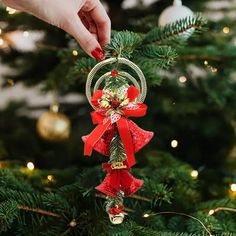 a hand holding an ornament on top of a christmas tree