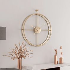 a clock is hanging on the wall next to a vase with some flowers in it