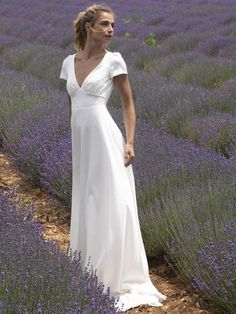 a woman standing in a lavender field wearing a white dress and holding her hand on her hip