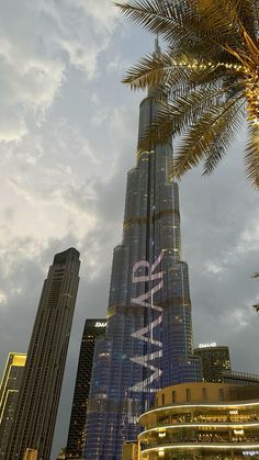 the tallest building in the world is lit up with lights and palm trees around it