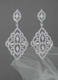 a pair of white diamond earrings on top of a veil