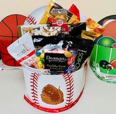 a bucket filled with candy and snacks on top of a white table next to a basketball