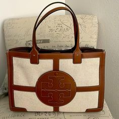 Never Used Tory Burch Leather And Material Tote. Immaculate Condition Luxury Beige Monogram Canvas Bag, Tory Burch Handbag, Designer Beige Shoulder Bag With Double Handle, Beige Monogram Canvas Satchel Bag, Designer Beige Shoulder Bag With Handles, Designer Beige Shoulder Bag For Errands, Beige Monogram Canvas Top Handle Shoulder Bag, Designer Beige Shoulder Bag With Removable Pouch, Beige Rectangular Monogram Canvas Shoulder Bag